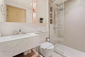 A modern bathroom with a marble countertop, a glass shower enclosure, and a wooden cabinet. - Silkhaus Premium 2BR in Golf Grand Dubai Hills (Dubai)