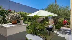 An outdoor patio area with a table and chairs, a potted plant, and a green umbrella. - Klarić Residence (Zadar)