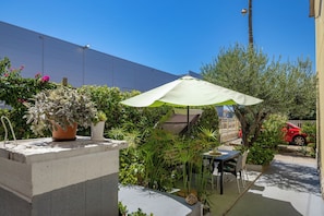 An outdoor patio area with a table and chairs, a potted plant, and a green umbrella. - Klarić Residence (Zadar)