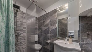 A modern bathroom with a shower, toilet, and sink. - Klarić Residence (Zadar)