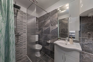 A modern bathroom with a shower, toilet, and sink. - Klarić Residence (Zadar)