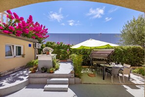 A patio area with a table and chairs, surrounded by potted plants and a white wall. - Klarić Residence (Zadar)