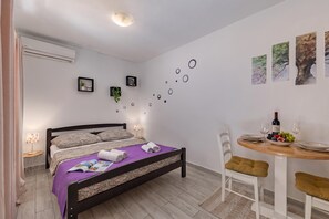 A bedroom with a bed, bedside tables, a small dining table with chairs, and wall decorations. - Klarić Residence (Zadar)