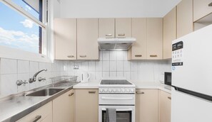 Una cocina compacta con estufa, horno, fregadero y refrigerador.