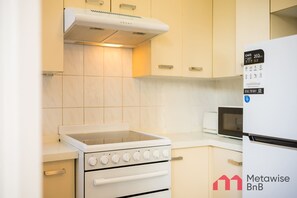 A kitchen with a white stove, oven, and microwave, a white refrigerator, and light-colored cabinets.