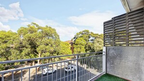 A balcony with a view of a street and trees. - Metawise 2BR Apt Brightest in Brighton (Sydney)