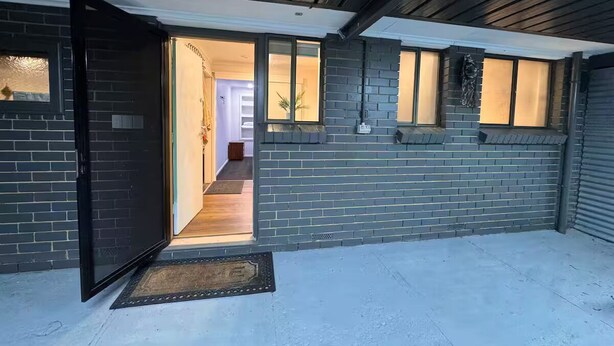 En modern byggnad med en fasad av tegel, en entré med glasdörr och en synlig korridor inuti.