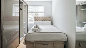 Hotellihuone, jossa on sänky, vaatekaappi ja ikkuna, jossa on sälekaihtimet.