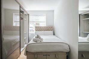 A hotel room with a bed, a wardrobe, and a window with blinds. - Modern 3-bedroom Home Near Westfield Central Lond (London)