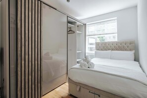 A bedroom with a bed, a wardrobe, and a window. - Modern 3-bedroom Home Near Westfield Central Lond (London)
