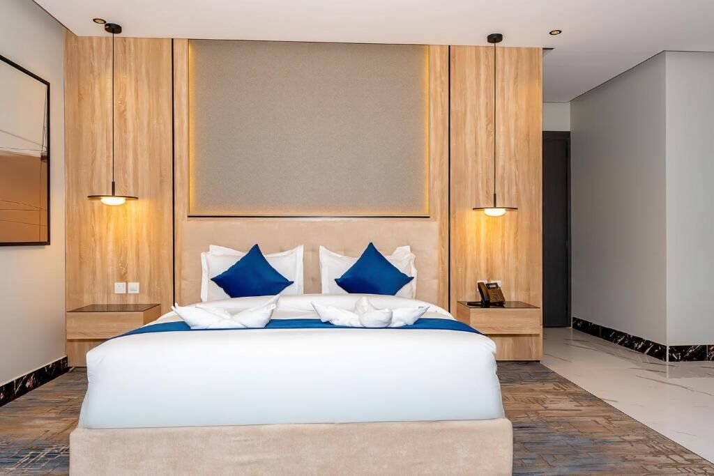 A hotel room with a large bed, two bedside tables, and a headboard.