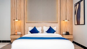 Une chambre d’hôtel avec un grand lit, deux tables de chevet et une œuvre d’art accrochée au mur.