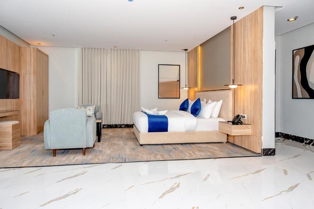 Une chambre d’hôtel moderne dotée d’un grand lit, d’un coin salon, d’une télévision et d’une grande œuvre d’art accrochée au mur.