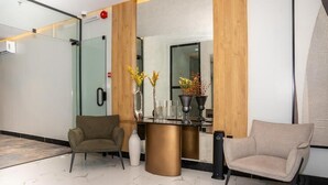 Un espace d’accueil doté d’une cloison en verre, de deux canapés, d’un comptoir de réception et de plantes décoratives.