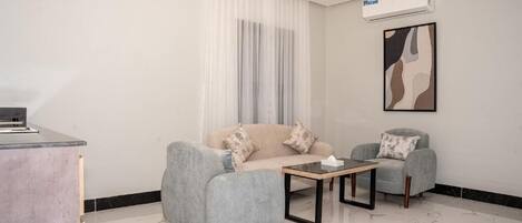 Una sala de estar moderna con un sofá, dos sillones, una mesita de centro y un escritorio pequeño.