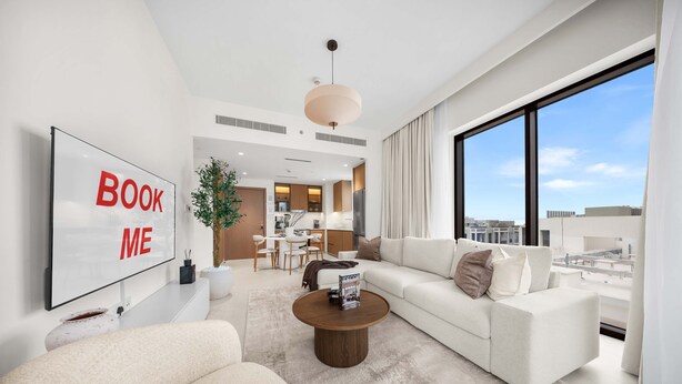 A modern living room with a large flat-screen TV, a sofa, a coffee table, and a view of the city through large windows. - Free Housekeeping Visits During Your Stay - Stayshort - Peaceful 1-bedroom in Dubai Creek Harbour - Sleeps 4 (Dubai)