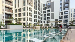 A modern hotel with a swimming pool, lounge chairs, and a well-maintained garden. - Free Housekeeping Visits During Your Stay - Stayshort - Peaceful 1-bedroom in Dubai Creek Harbour - Sleeps 4 (Dubai)