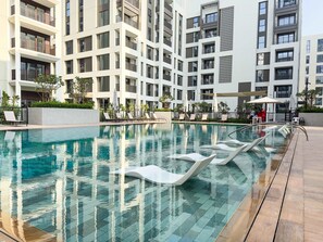 Ein modernes Hotel mit Schwimmbad, Liegestühlen und einem gepflegten Garten.