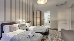 A hotel room with two beds, a nightstand, a wardrobe, and a door leading to a bathroom. - Proconsolo 9S in Firenze (Florence)