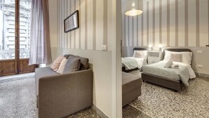 A hotel room with a sofa, a bed with two pillows, a small table, and a wall-mounted lamp. - Proconsolo 9S in Firenze (Florence)
