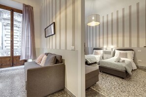 A hotel room with a sofa, a bed with two pillows, a small table, and a wall-mounted lamp. - Proconsolo 9S in Firenze (Florence)