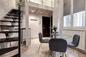 Ein modernes Interieur mit einer Treppe, einem Glastisch mit Stühlen und einer Tür zu einem weiteren Raum.