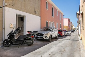 Eine schmale Straße mit parkenden Fahrzeugen und Gebäuden.