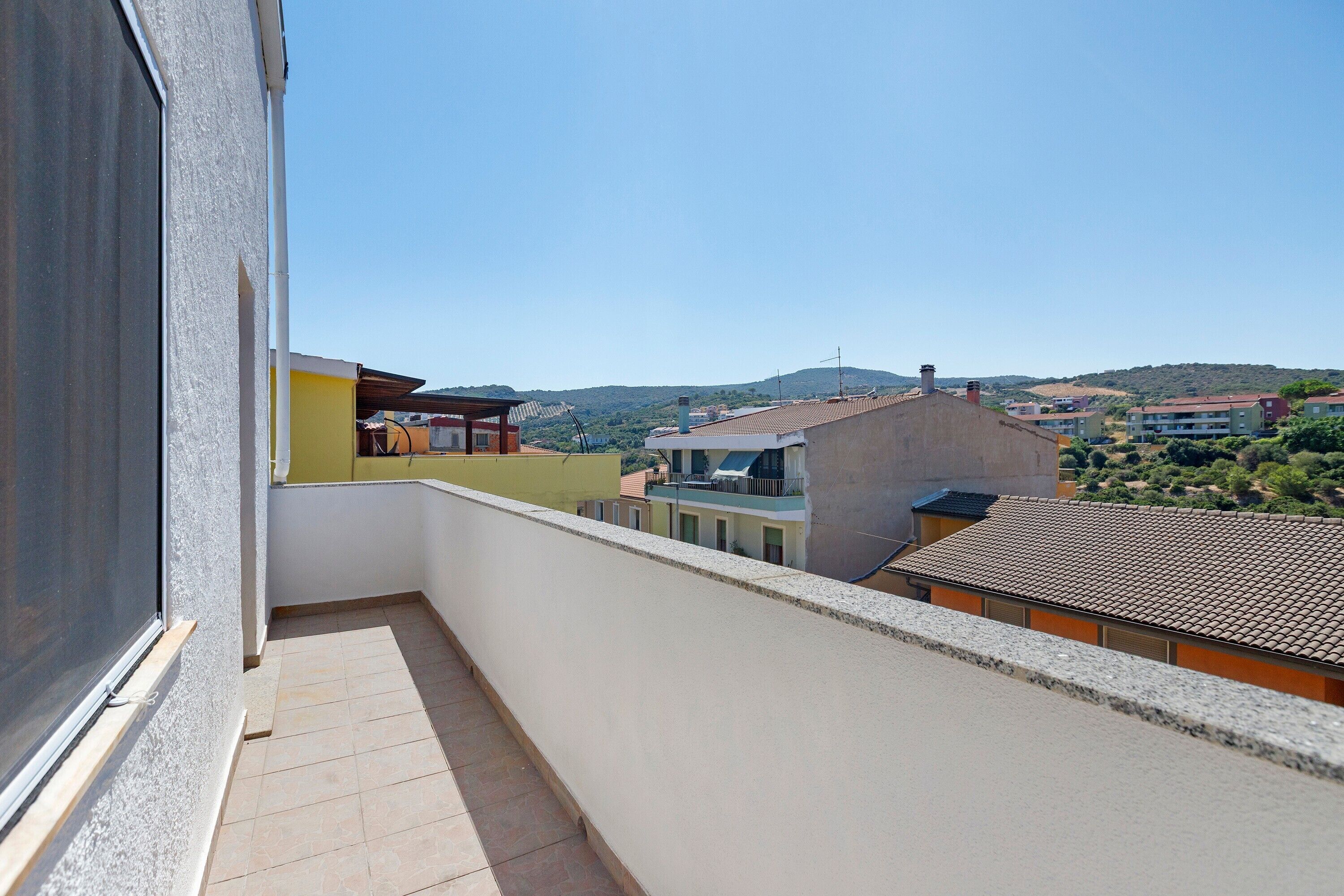 A balcony with a clear view of a residential area, including buildings and a hilly landscape.