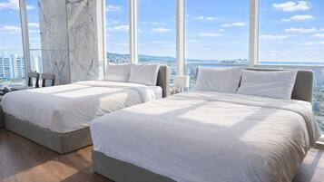 A hotel room with two beds, a marble wall, and a city view.