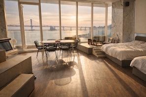 A modern bedroom with a large window overlooking a bridge and cityscape.