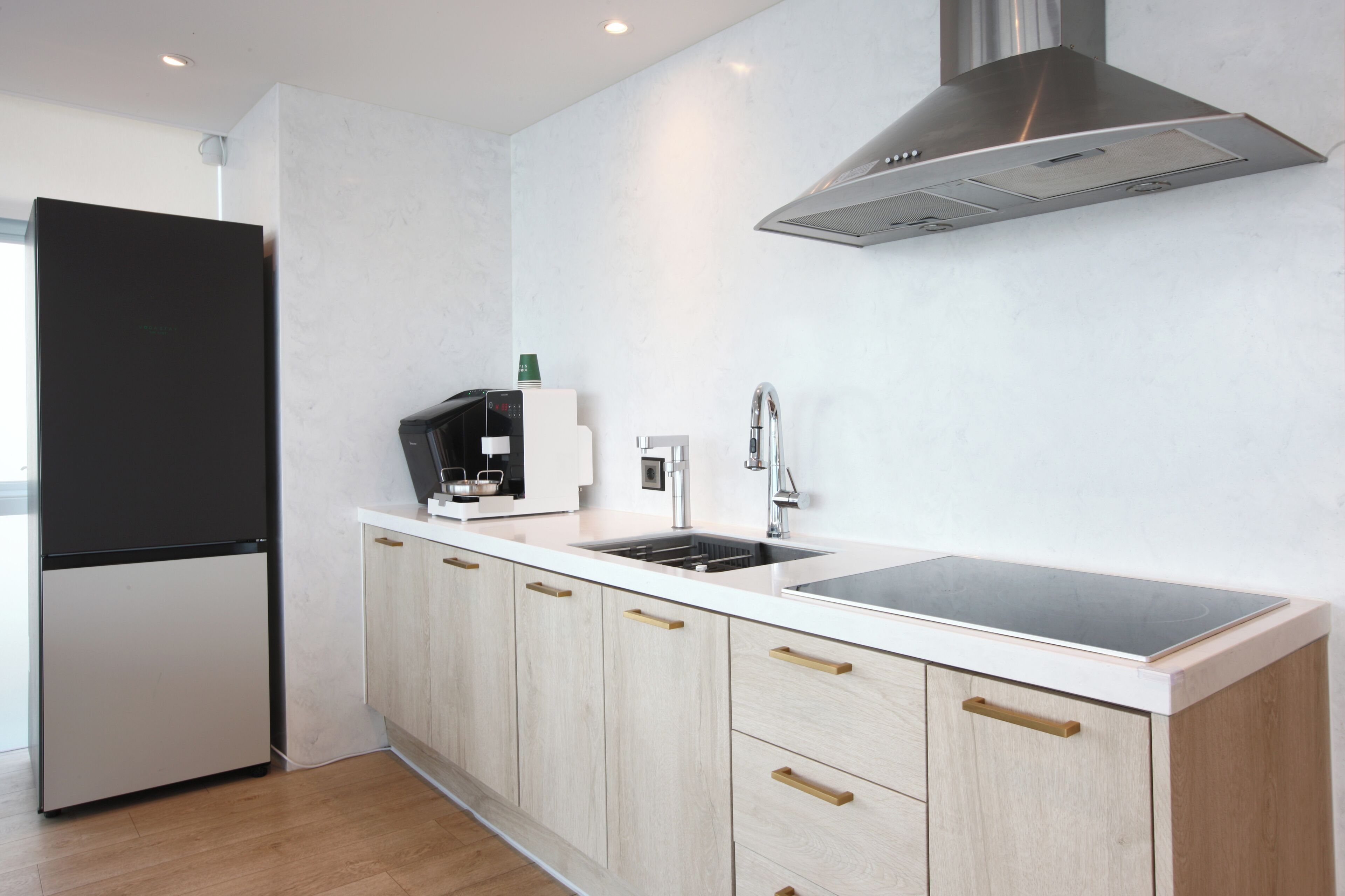 Una cocina moderna con refrigerador empotrado, campana de acero inoxidable y pileta doble.
