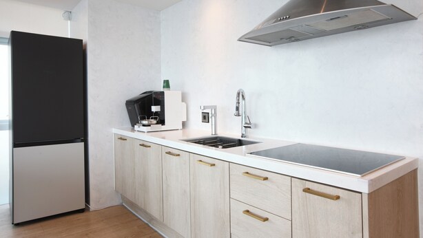 A modern kitchen with a built-in refrigerator, a stainless steel range hood, and a double sink.
