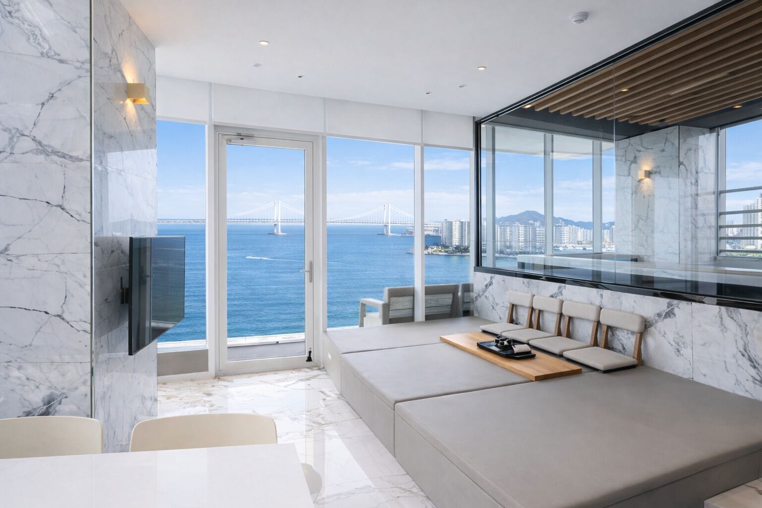 A modern room with a large window, a seating area, and a flat-screen TV.