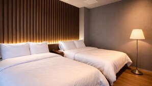 A hotel room with two beds, a modern ceiling design, and a floor lamp.