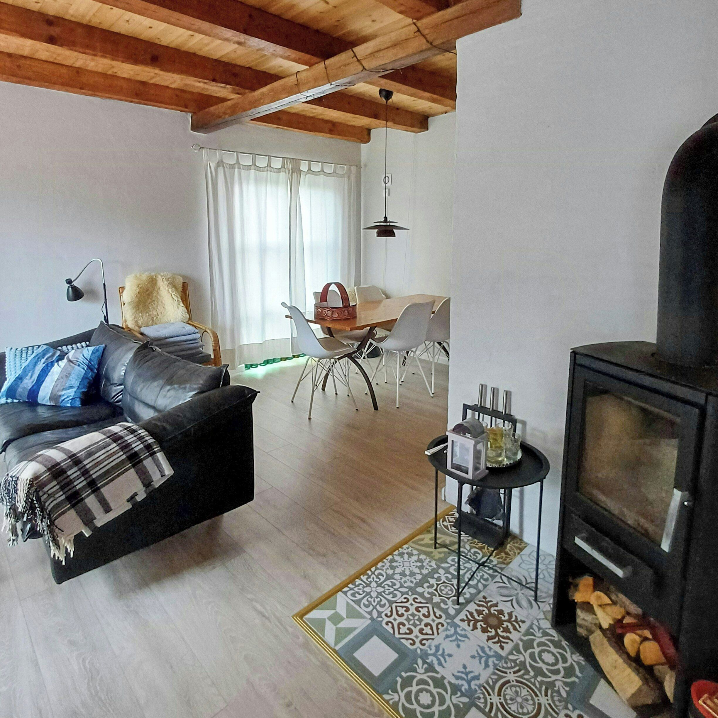 A living room with a sofa, a dining table with chairs, a fireplace, and a patterned rug.