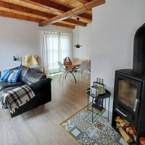 Ein Wohnzimmer mit einer Couch, einem Esstisch mit Stühlen, einem Kamin und einem gemusterten Teppich.