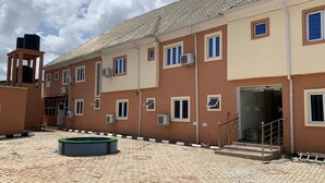 A multi-story building with a courtyard, outdoor air conditioning units, and a small pool. - Plus 234 Hotels and Suites (Ibadan)