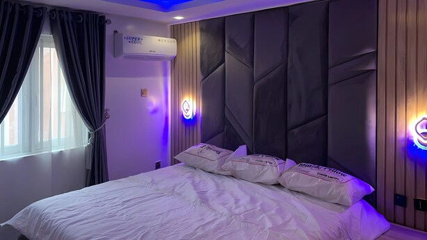 A modern bedroom with a bed, air conditioning unit, and decorative lighting. - Plus 234 Hotels and Suites (Ibadan)