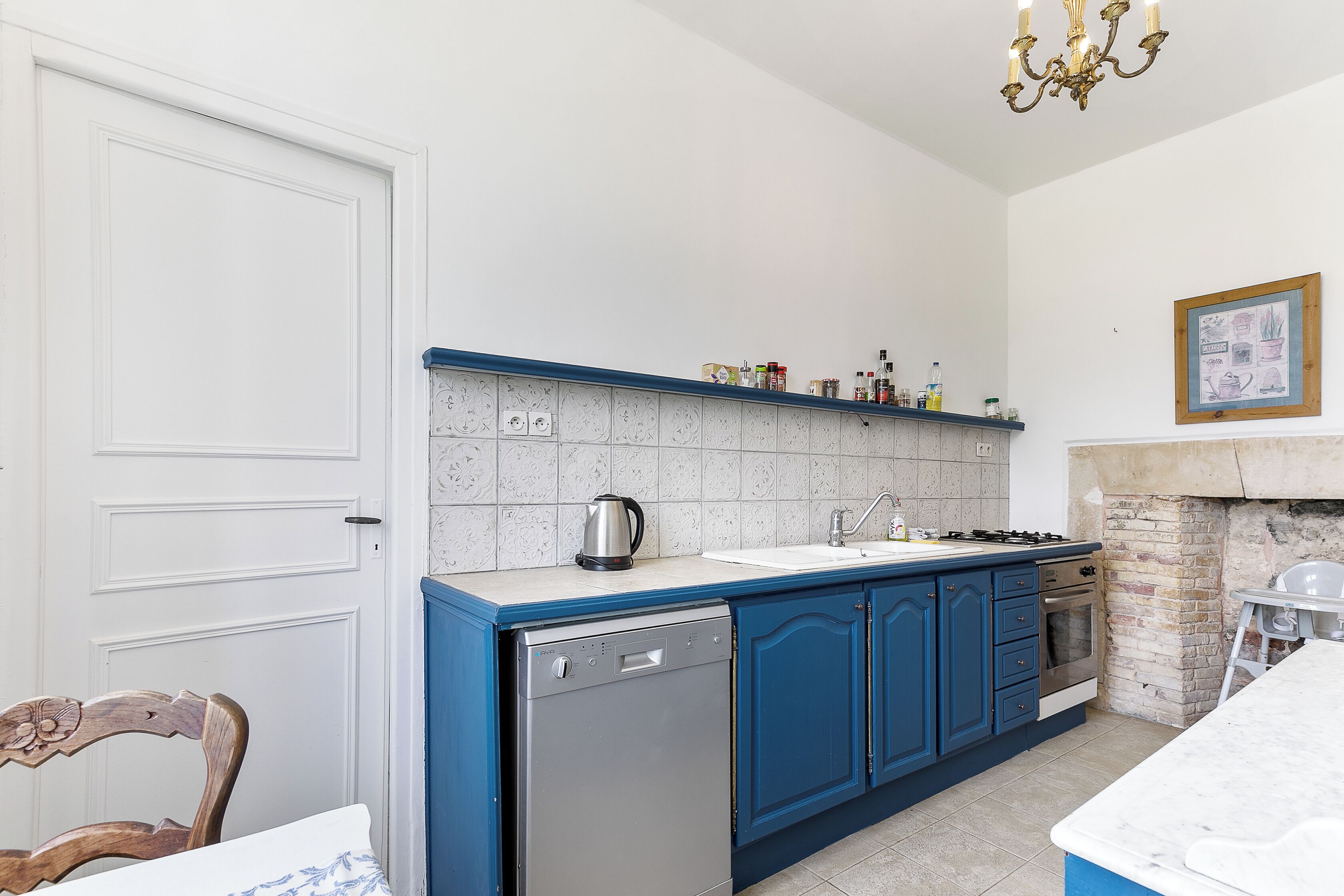Une cuisine avec des meubles de rangement bleus, un lave-vaisselle, une cuisinière et un évier.