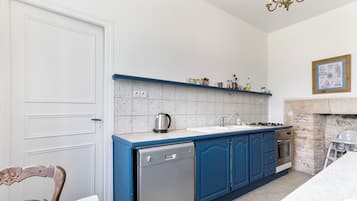 Une cuisine avec des meubles de rangement bleus, un lave-vaisselle, une cuisinière et un évier.