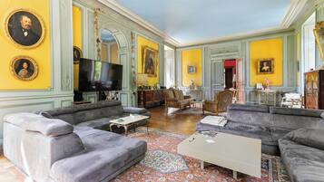 Un salon spacieux avec un grand canapé d’angle gris, un téléviseur à écran plat et un tapis à motifs.