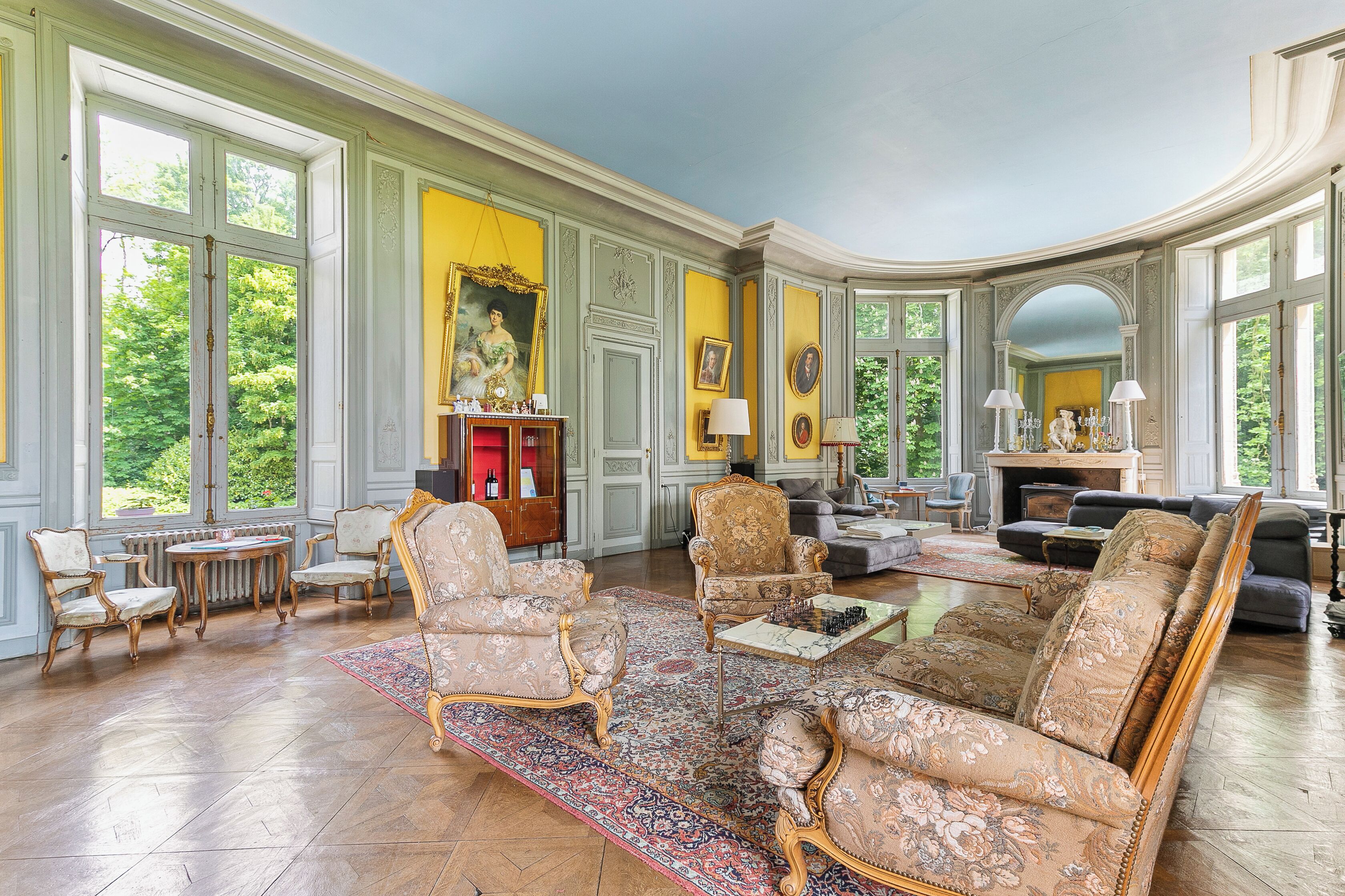 A spacious living room with a large window, a fireplace, and a chess table.