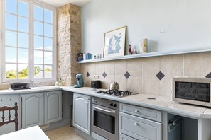 Una cocina con pared de piedra, una ventana y un microondas.