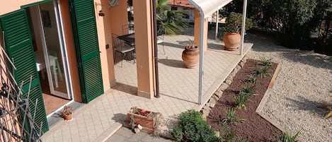 Eine überdachte Terrasse im Freien mit Blick auf das Meer, einem gefliesten Boden und Kübelpflanzen.