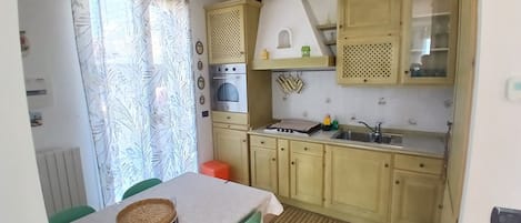 A kitchen with a dining table, a stove, and a sink.