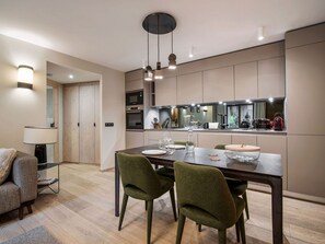 A modern kitchen with built-in appliances, a dining area with a table and chairs, and a lamp. - Ideal apartment, near slopes - 2 guests (La Tania)
