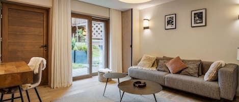 Una sala de estar moderna con una mesa de comedor de madera, un sofá, una mesa de centro y un amplio ventanal con cortinas.
