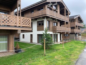 A multi-story building with balconies, wooden lattice railings, and a small tree in the foreground. - Ideal apartment, near slopes - 2 guests (La Tania)