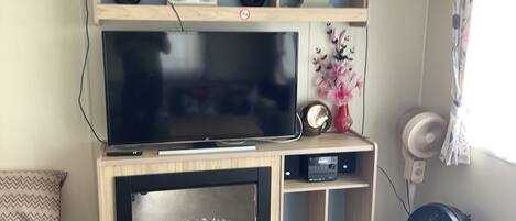 A television mounted on a wooden entertainment unit with a built-in fireplace below.