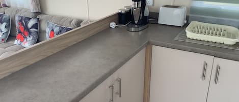 A kitchenette with a microwave, toaster, coffee maker, and a dish rack.